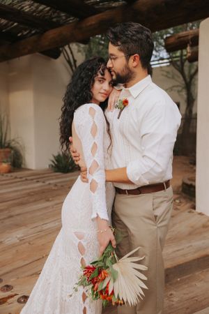 Wedding couple in white dress and khaki suit dancing at rustic desert venue.