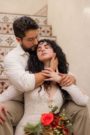 Romantic wedding portraits on decorative tiled steps with red rose bouquet.
