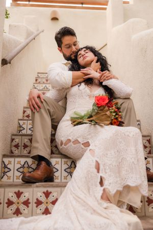 Romantic wedding portraits on southwestern tiled steps with red rose bouquet.