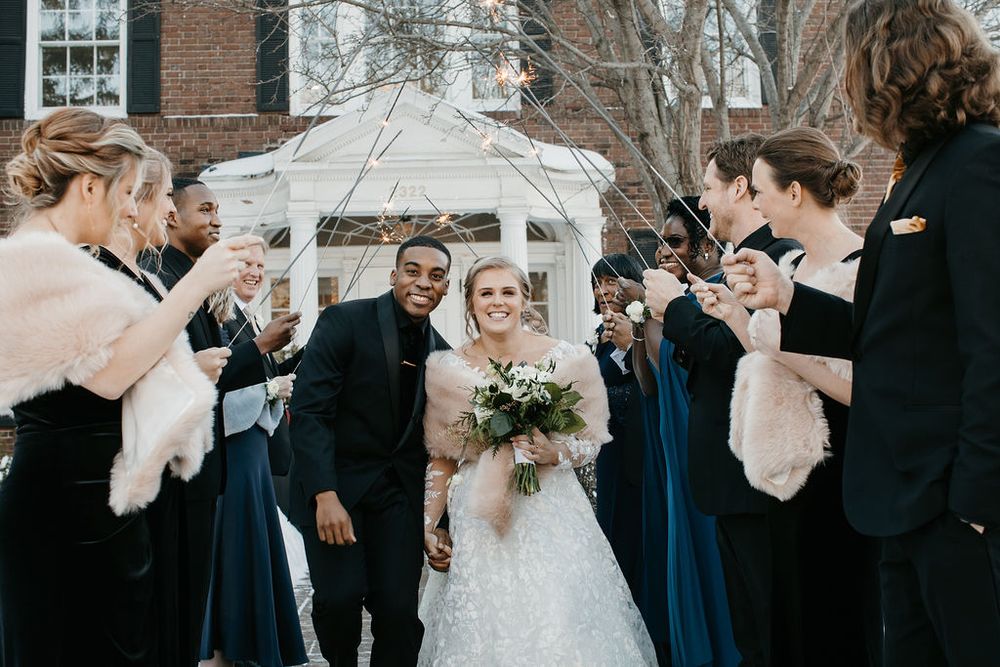Newlyweds celebrate joyful winter wedding exit with confetti and cheering bridal party.