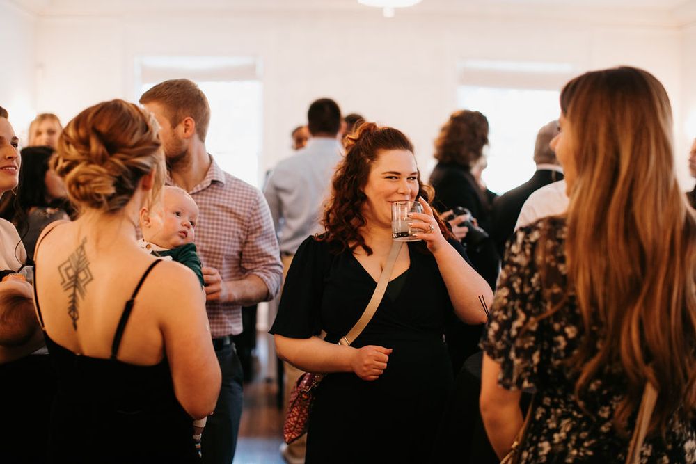 Guests mingle and enjoy drinks at casual indoor wedding reception celebration.