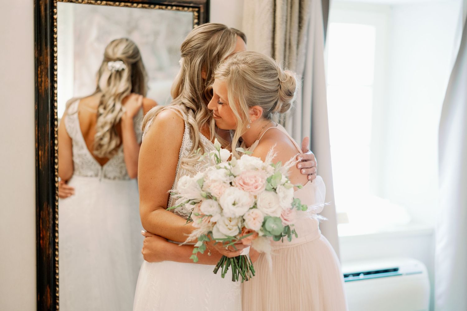 An emotional moment captured in the bridal suite with a bouquet of pink and white flowers.