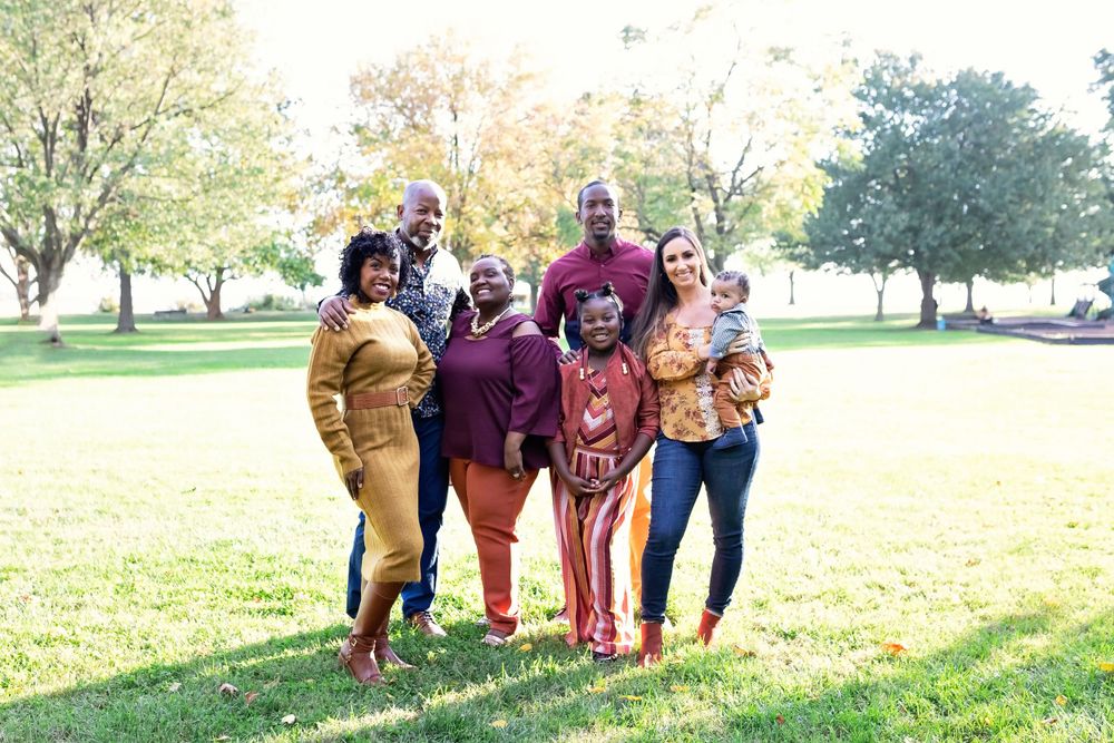 Happy family of seven posing together in a sunny park with autumn trees.