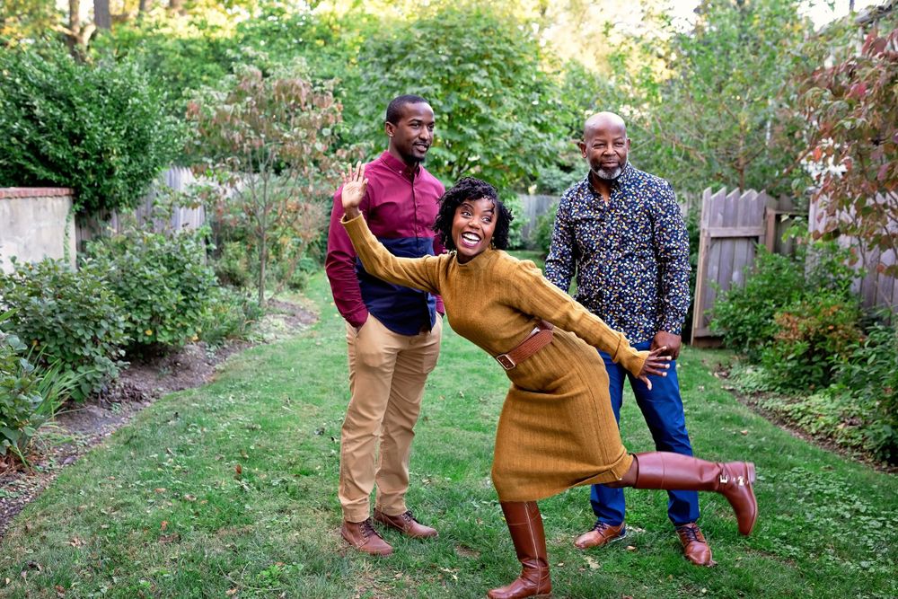 Three friends laughing and posing playfully in a green backyard garden.