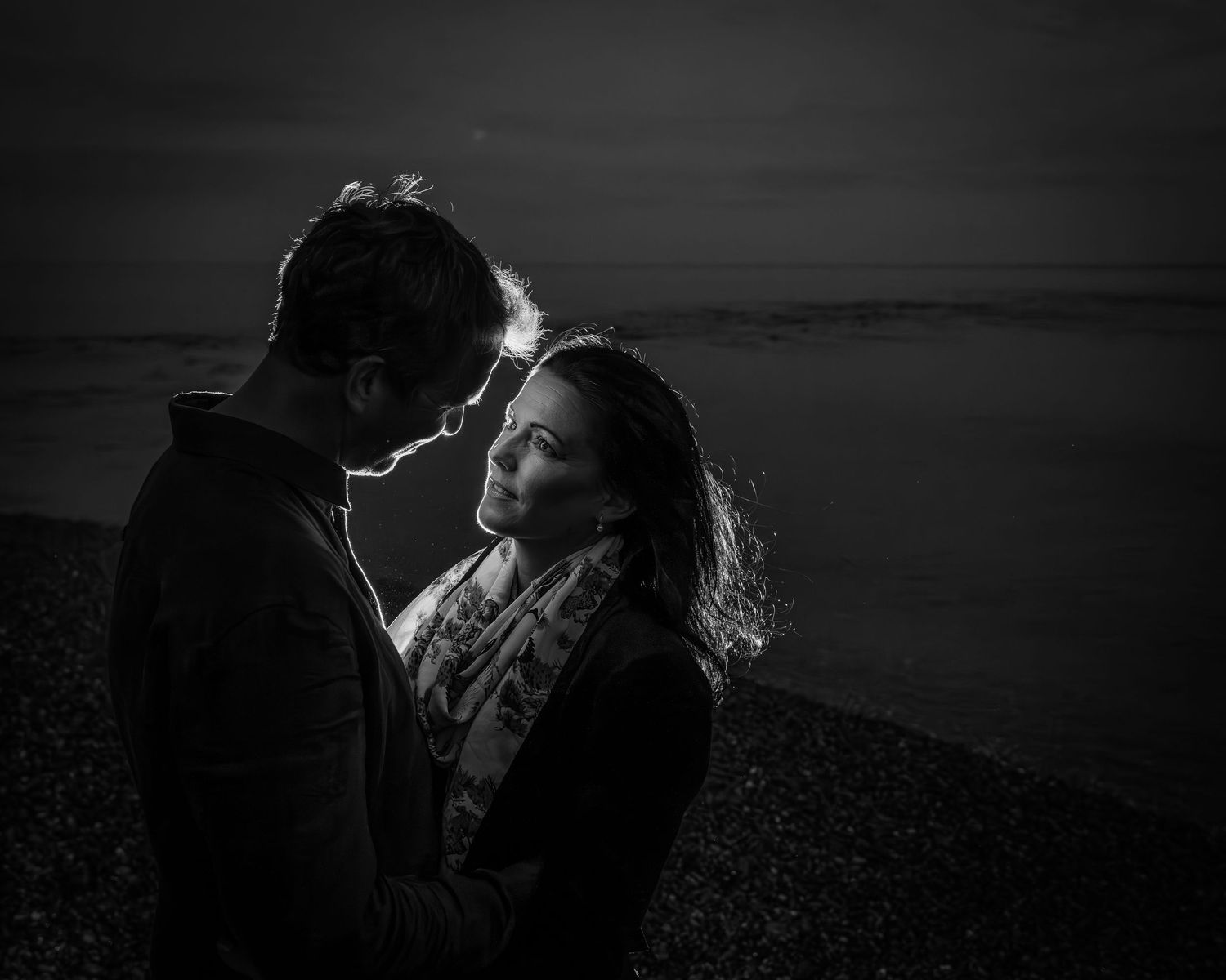 Dramatic black and white portrait of couple in moonlit evening setting.