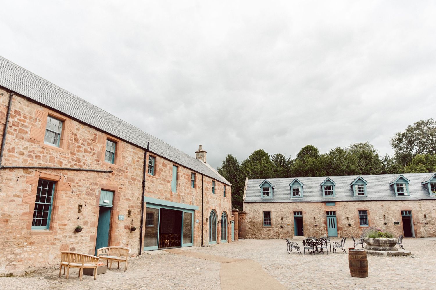 Panoramic view of historic brick wedding venue with string lights and outdoor seating.