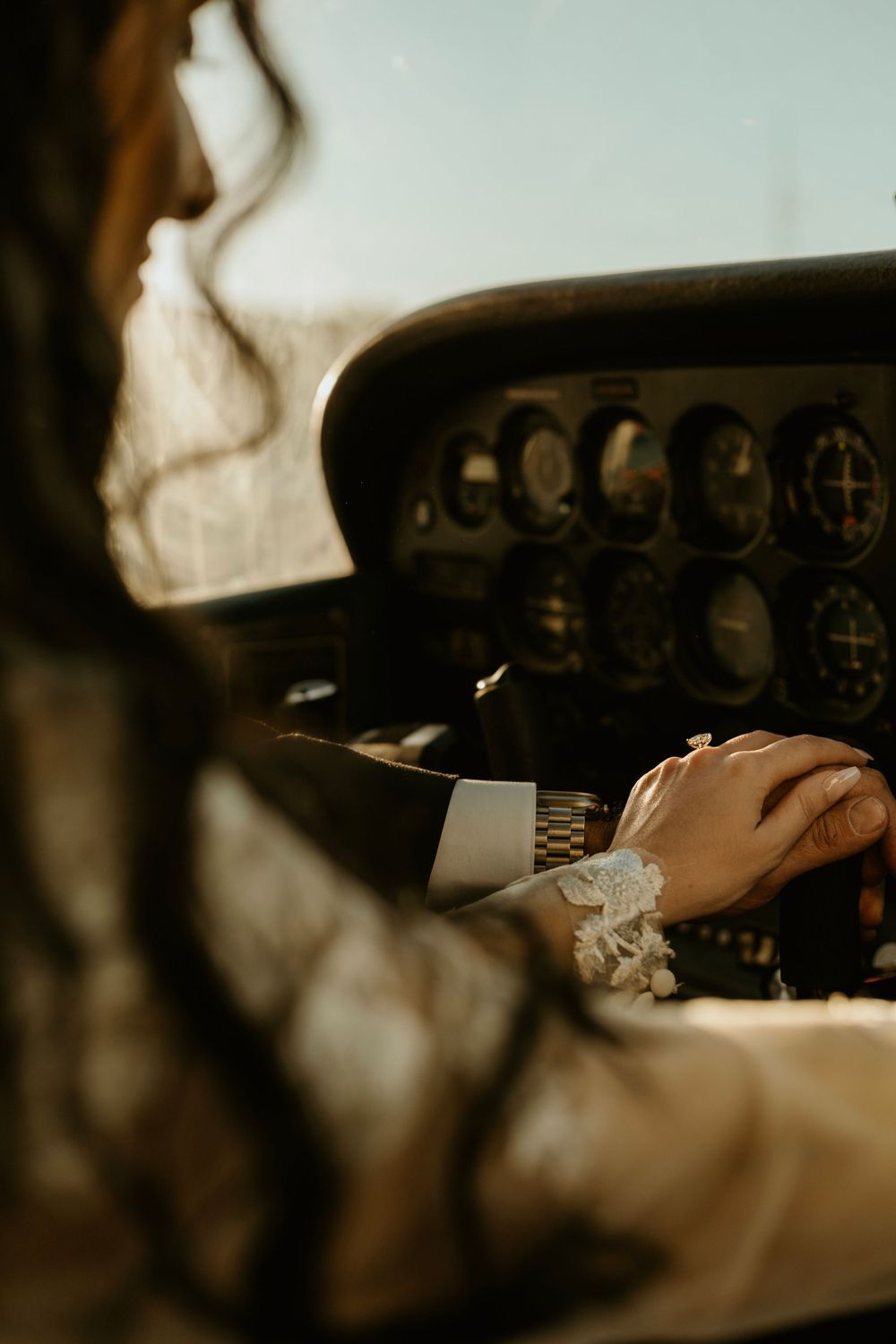 Close-up shot of hands on an airplane control panel wearing formal attire.