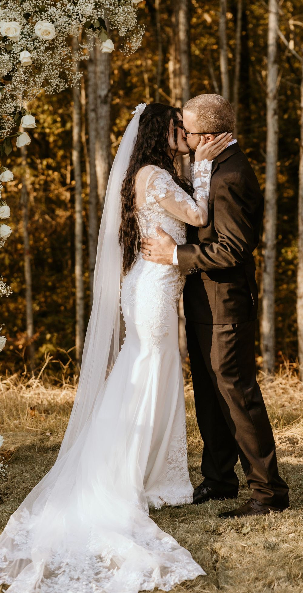 A romantic autumn wedding moment against a backdrop of golden forest trees.