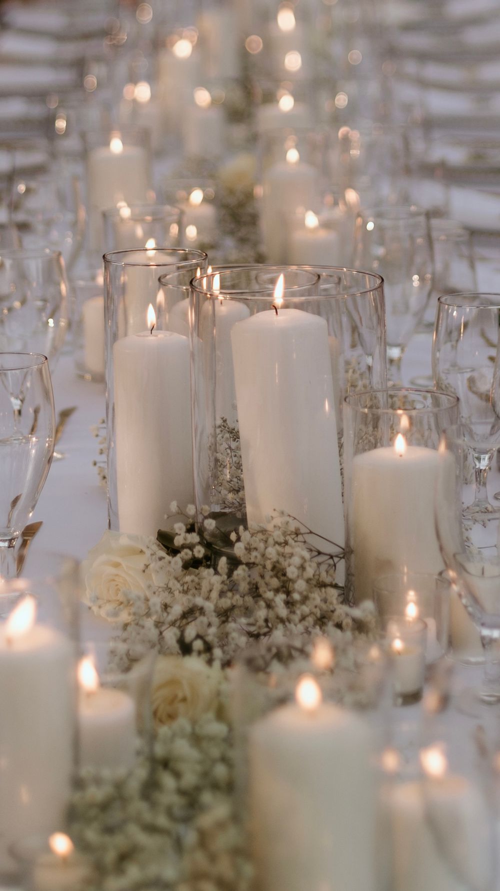 Elegant wedding reception table decor with white pillar candles and baby's breath flowers.