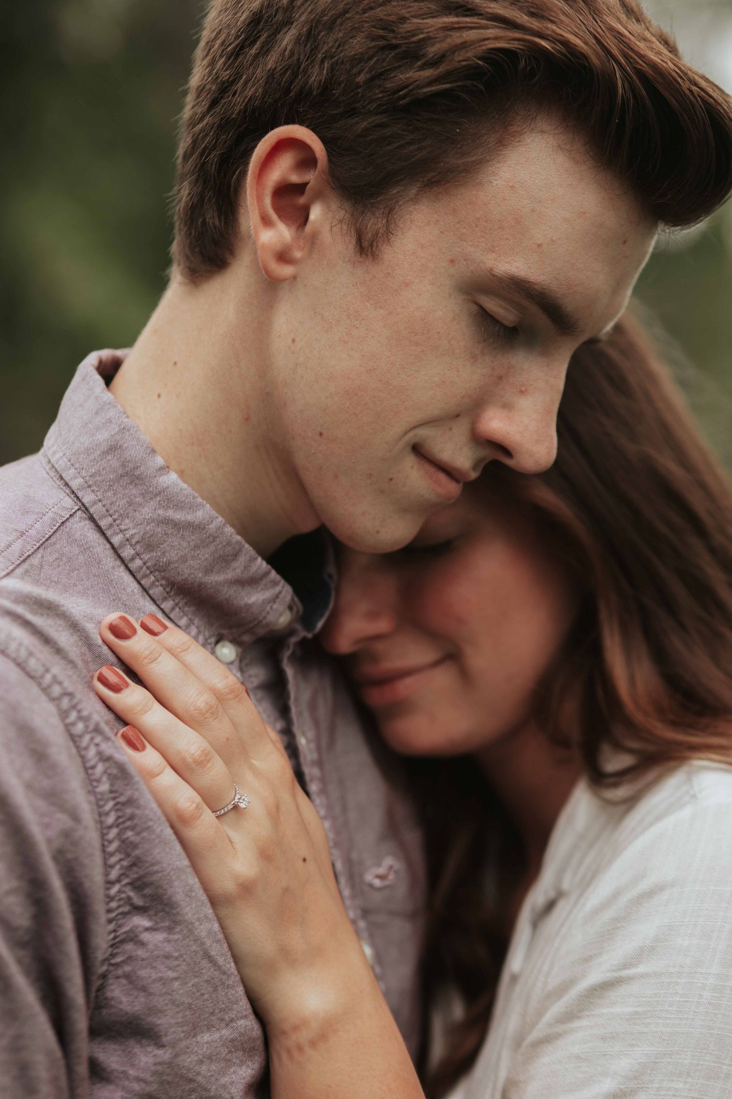 An intimate engagement photo showing a tender moment between a couple with her ring visible on display.