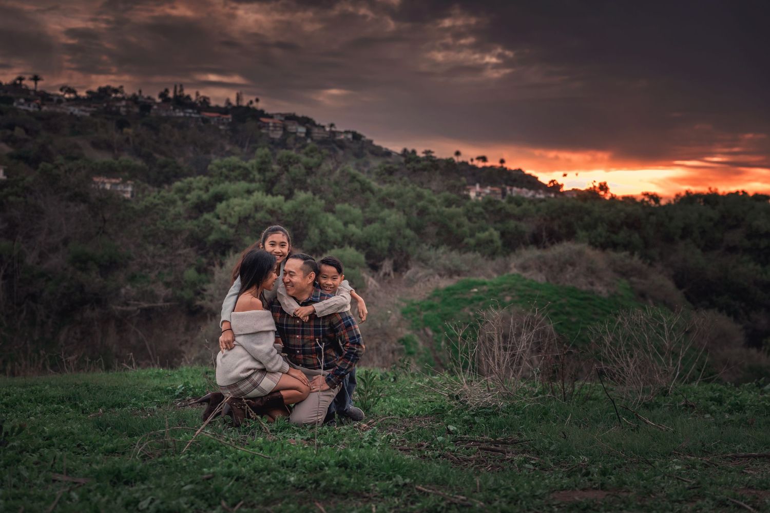 Sunset portrait in a grassy hilltop setting with dramatic sky.