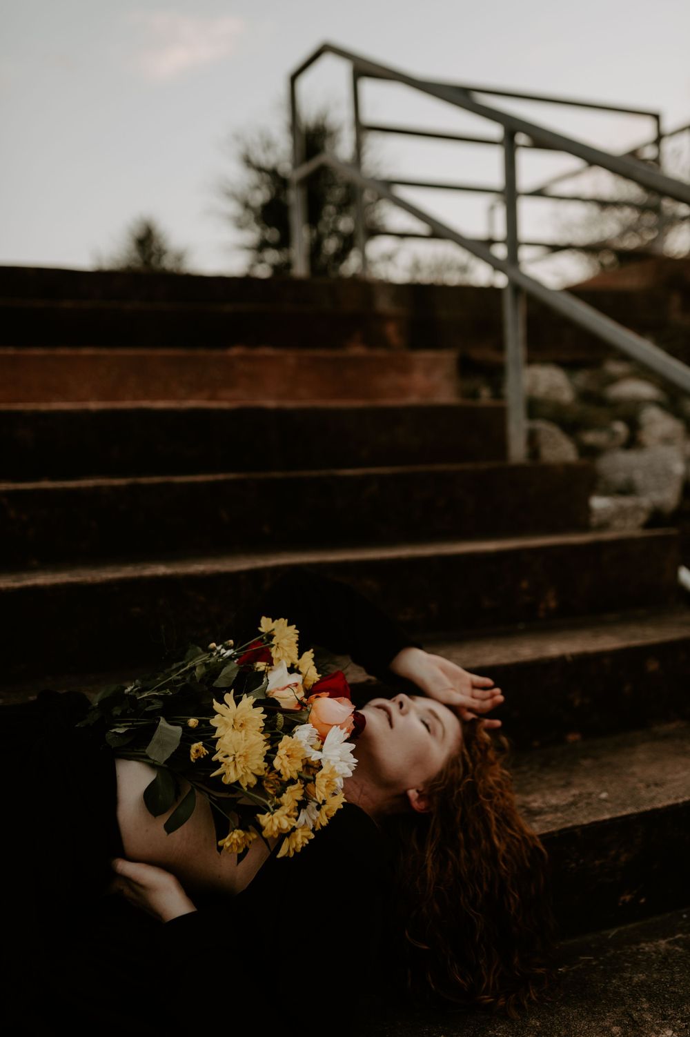 Artistic photo of someone resting on vintage wooden bleachers adorned with yellow and red flowers.