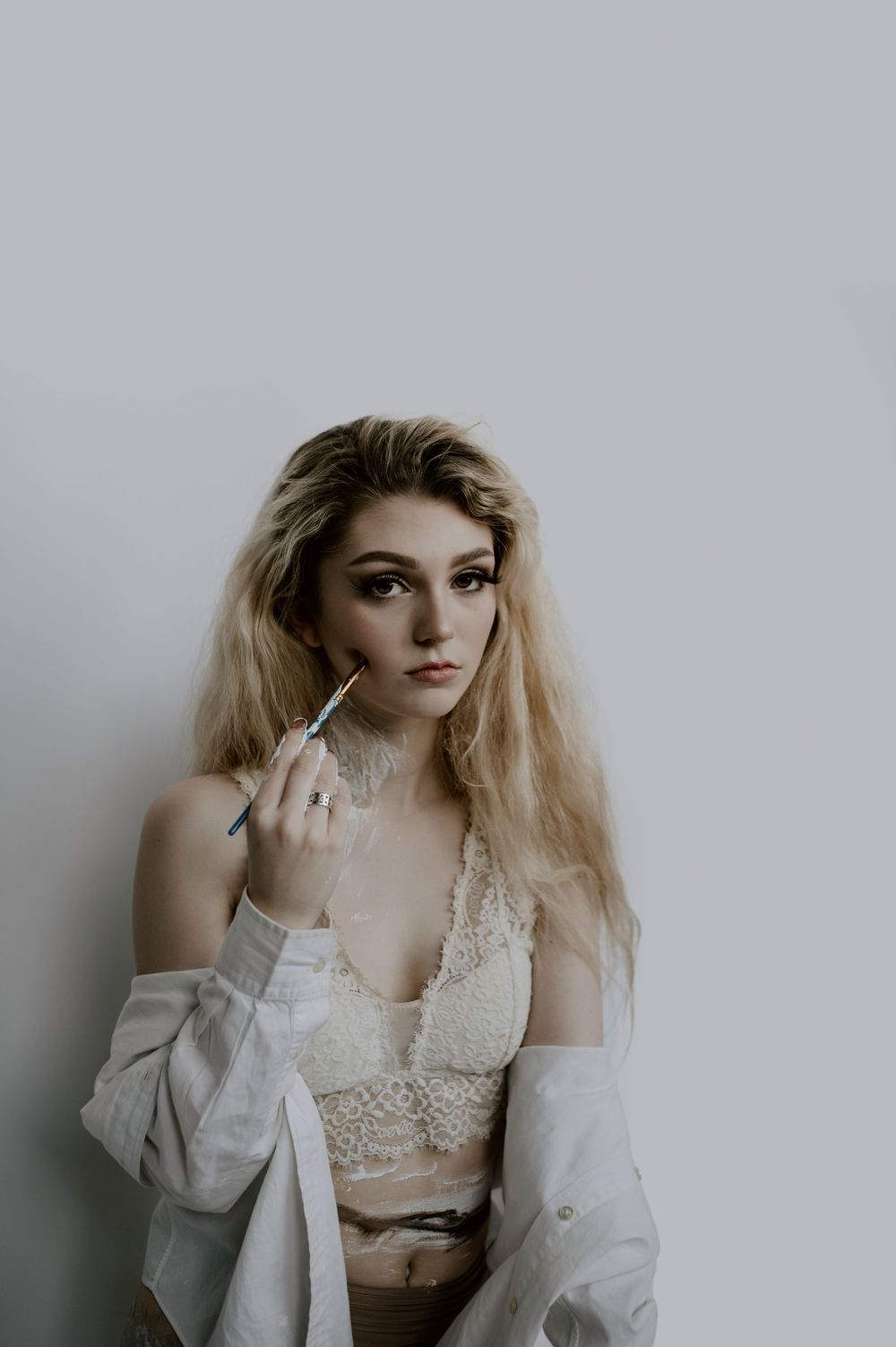 Artistic boudoir portrait featuring delicate lace lingerie and tousled blonde hair.