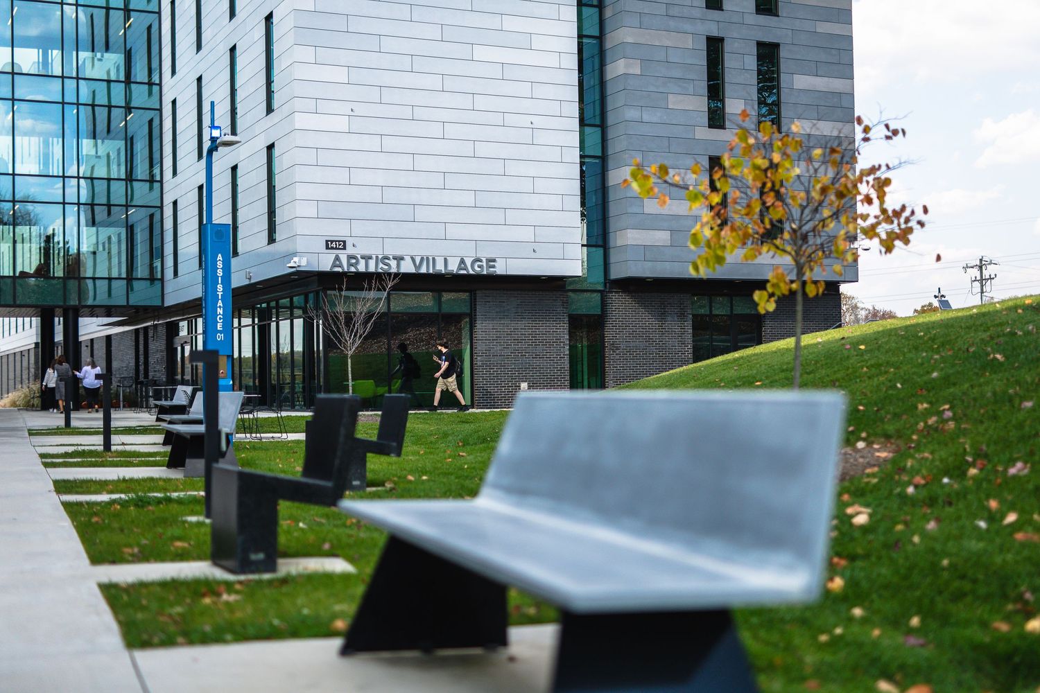 Modern metal benches line walkway outside contemporary university building.