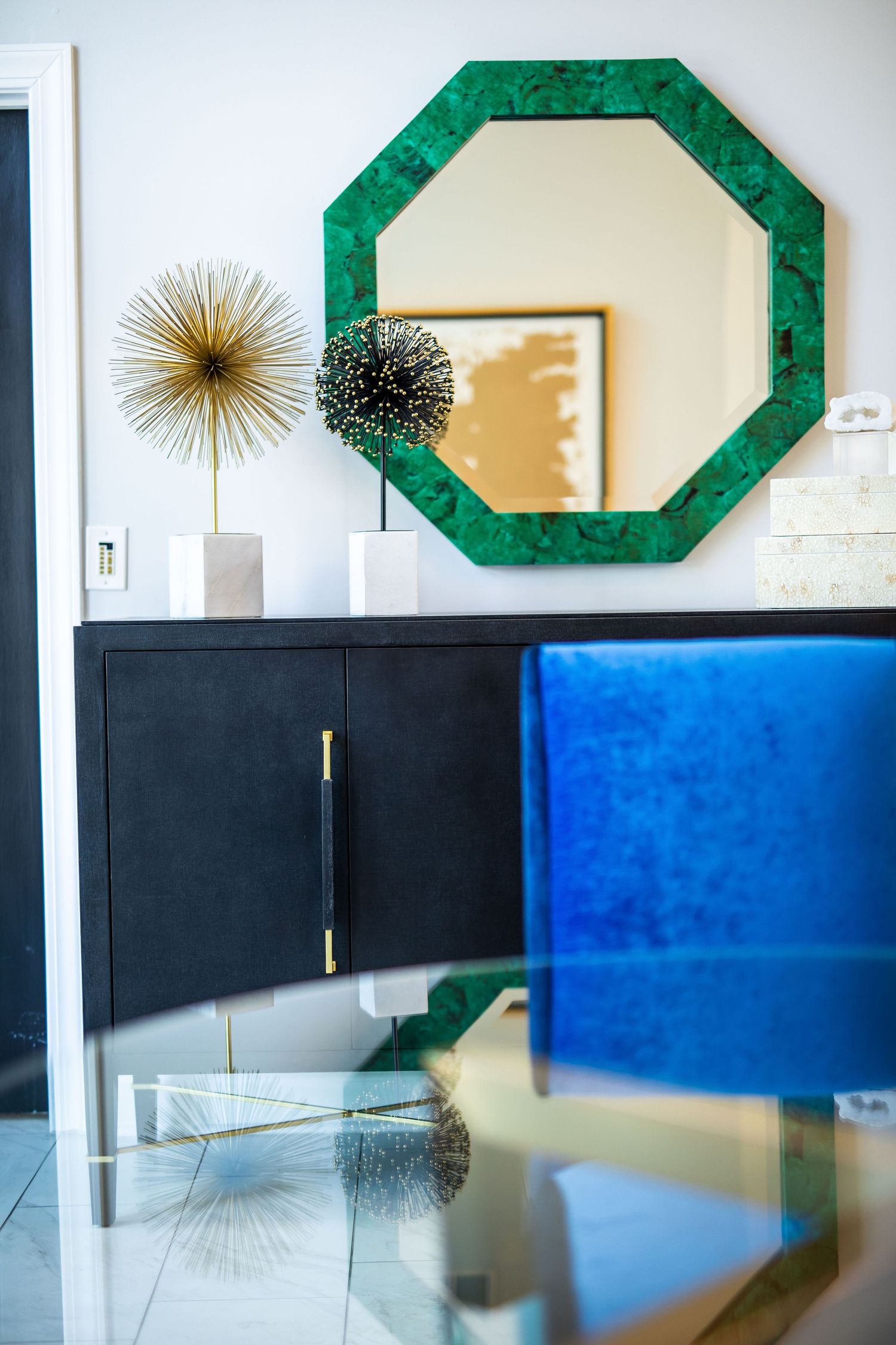 Modern room decor featuring an octagonal green mirror and sunburst wall art.