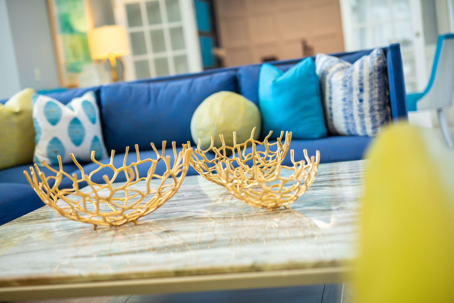 Coastal-style living room with blue sofa and decorative gold bowls on coffee table.