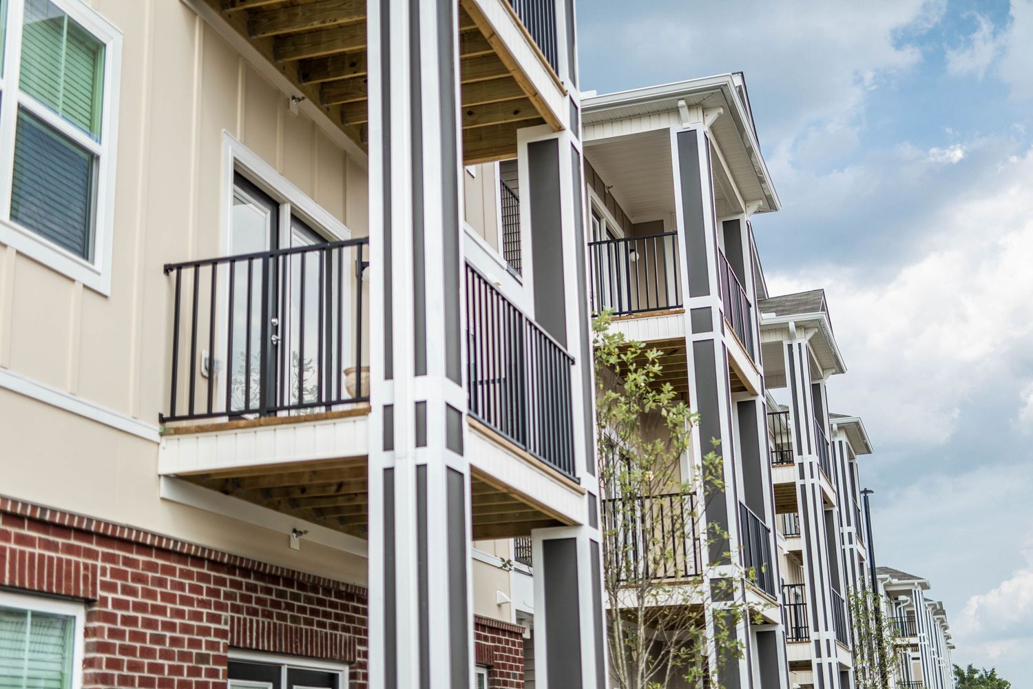 Modern townhouse exteriors with white columns and black railings against blue sky.