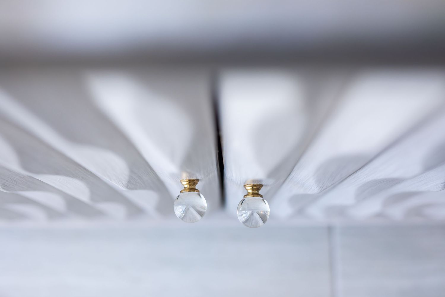 Two small decorative glass bottles with gold caps casting dramatic shadows.