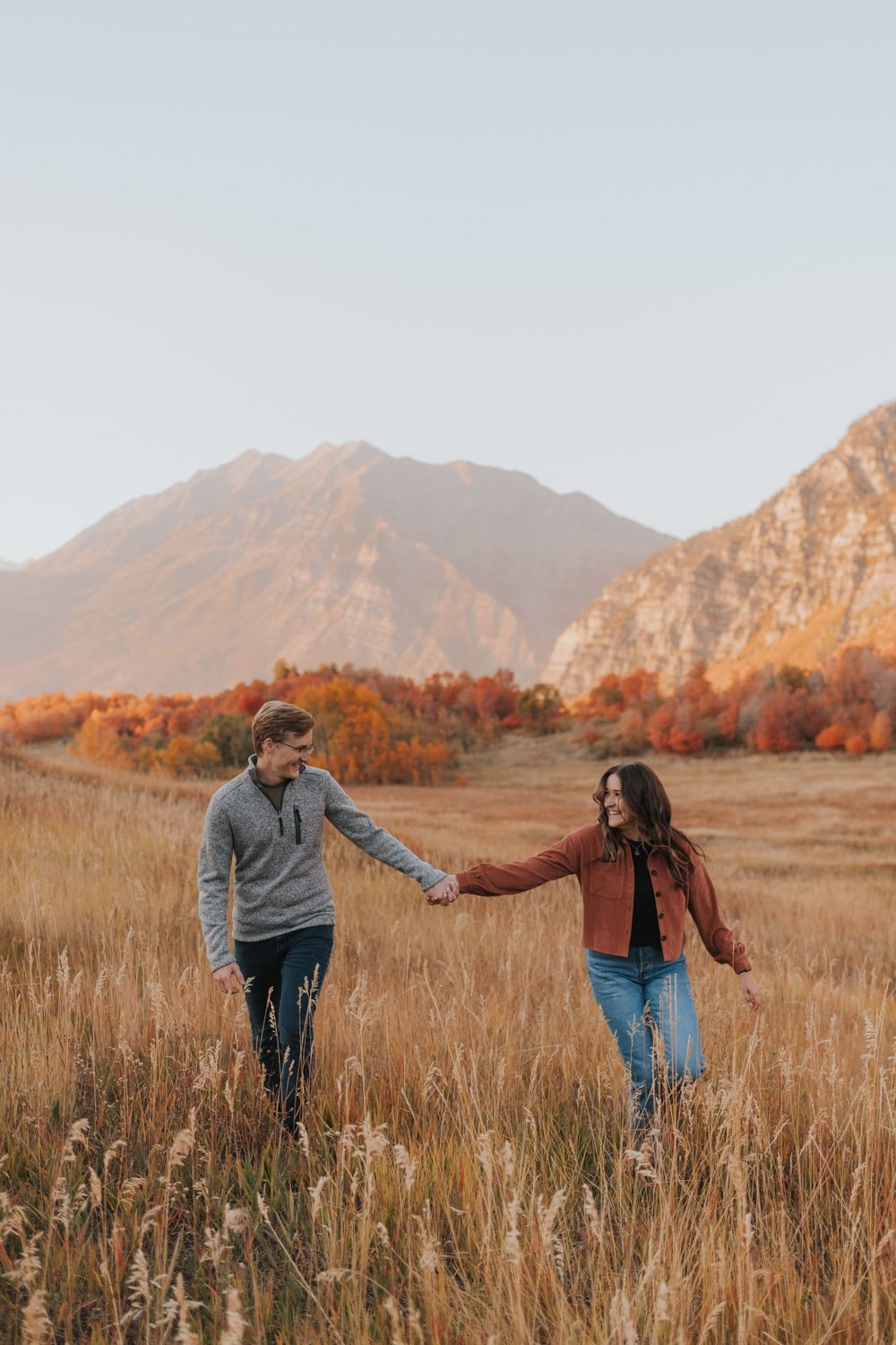 A couple laughs during a fall engagement session, photographed by Provo wedding photographer.