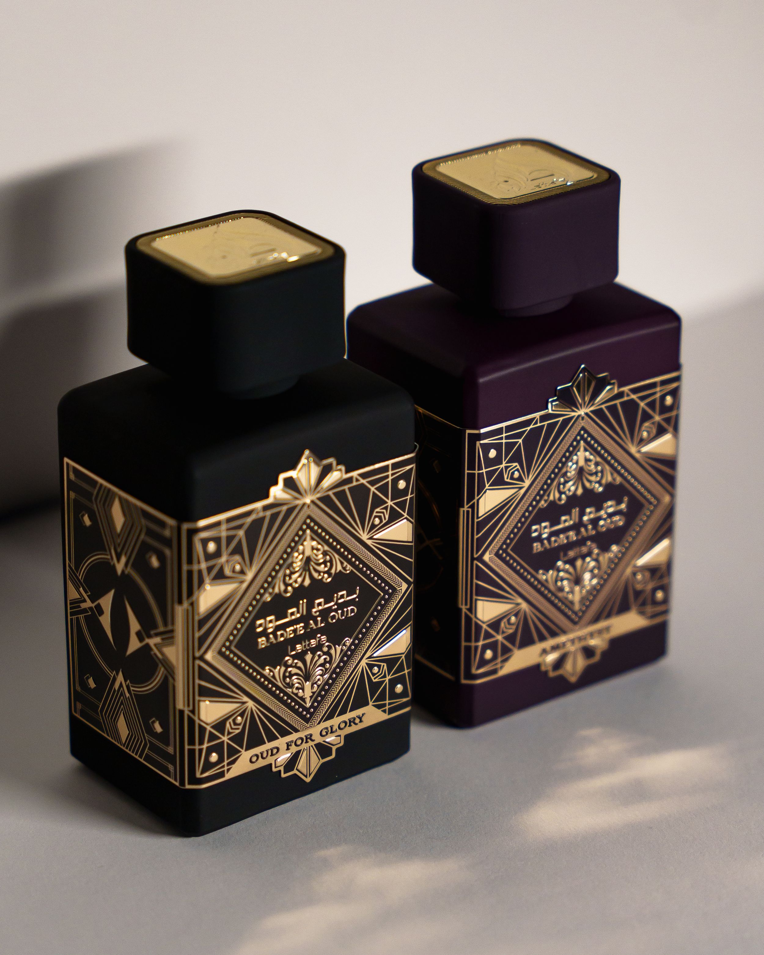 Two elegant perfume bottles with ornate gold geometric patterns on dark backgrounds.