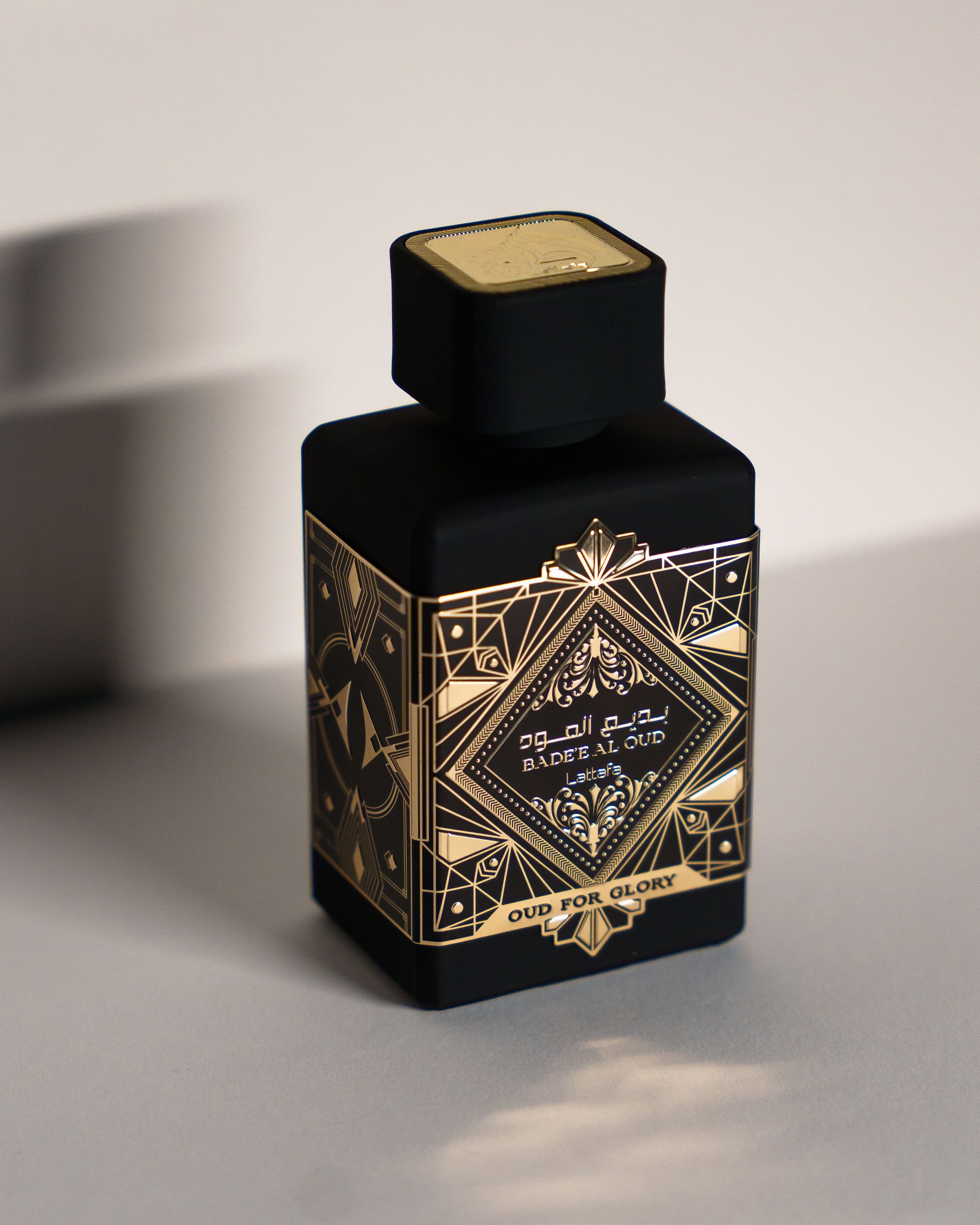 An ornate black perfume bottle with gold Art Deco geometric patterns and decorative details.