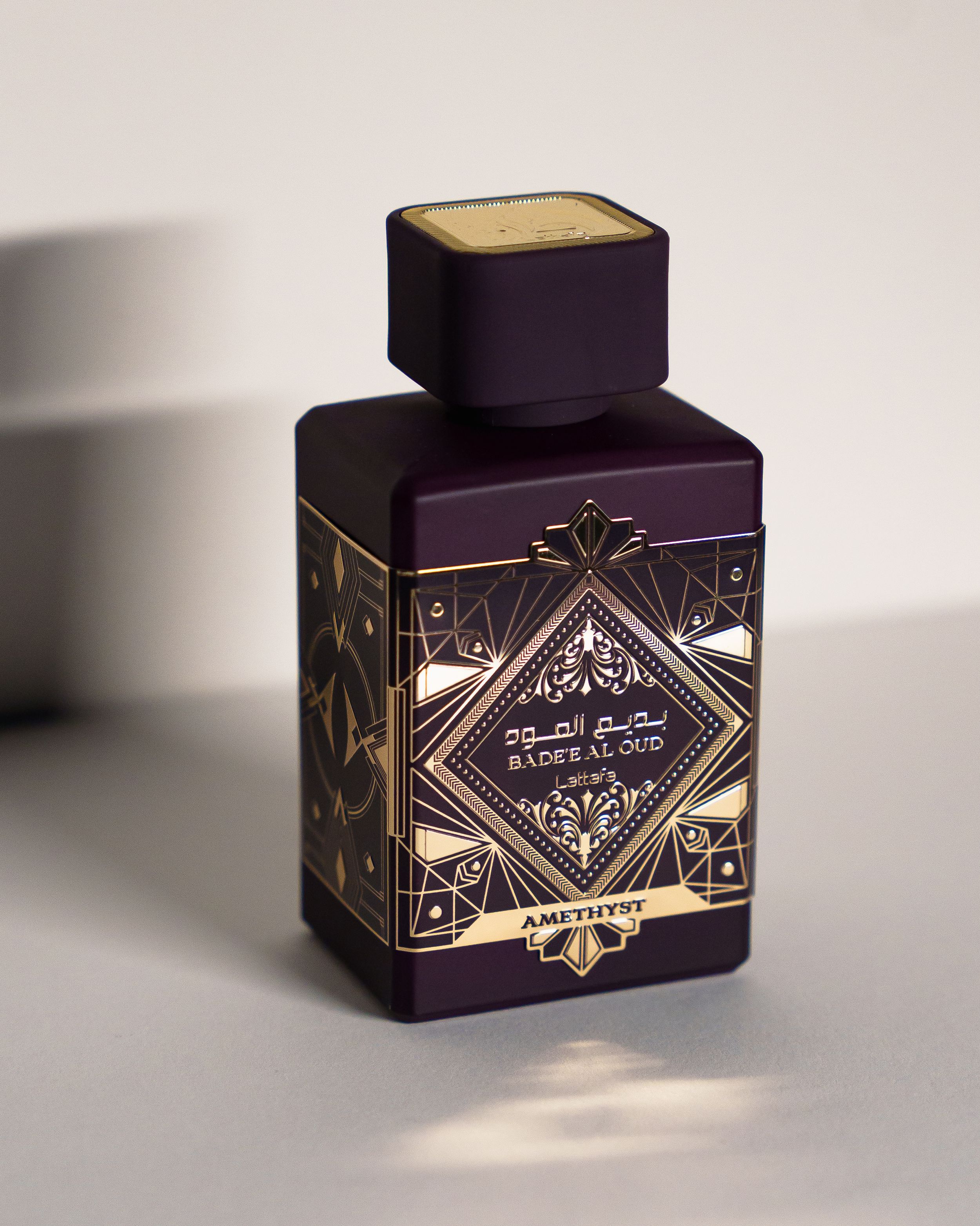 A deep purple perfume bottle featuring elegant gold geometric Art Deco designs.