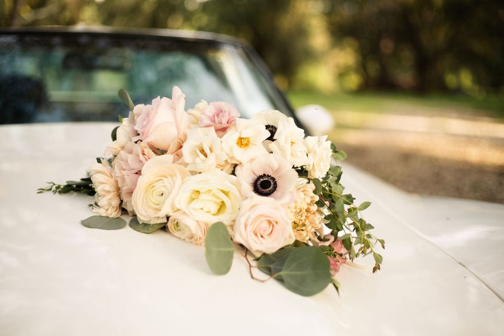Elegant floral arrangement with pink and cream roses on a white car hood.