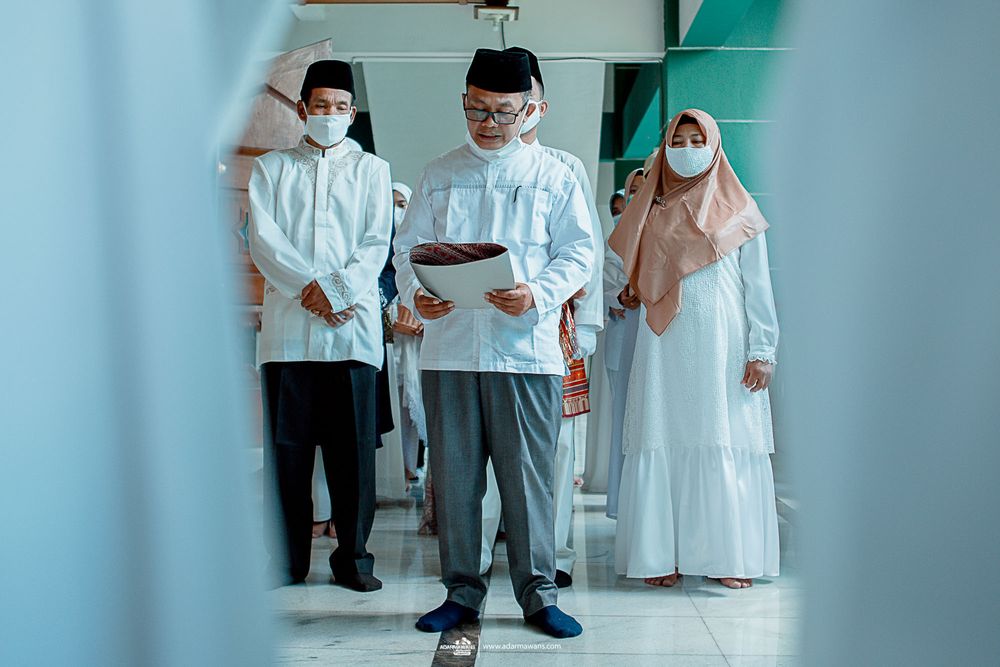 People in white Islamic clothing and face masks gathered for ceremony.