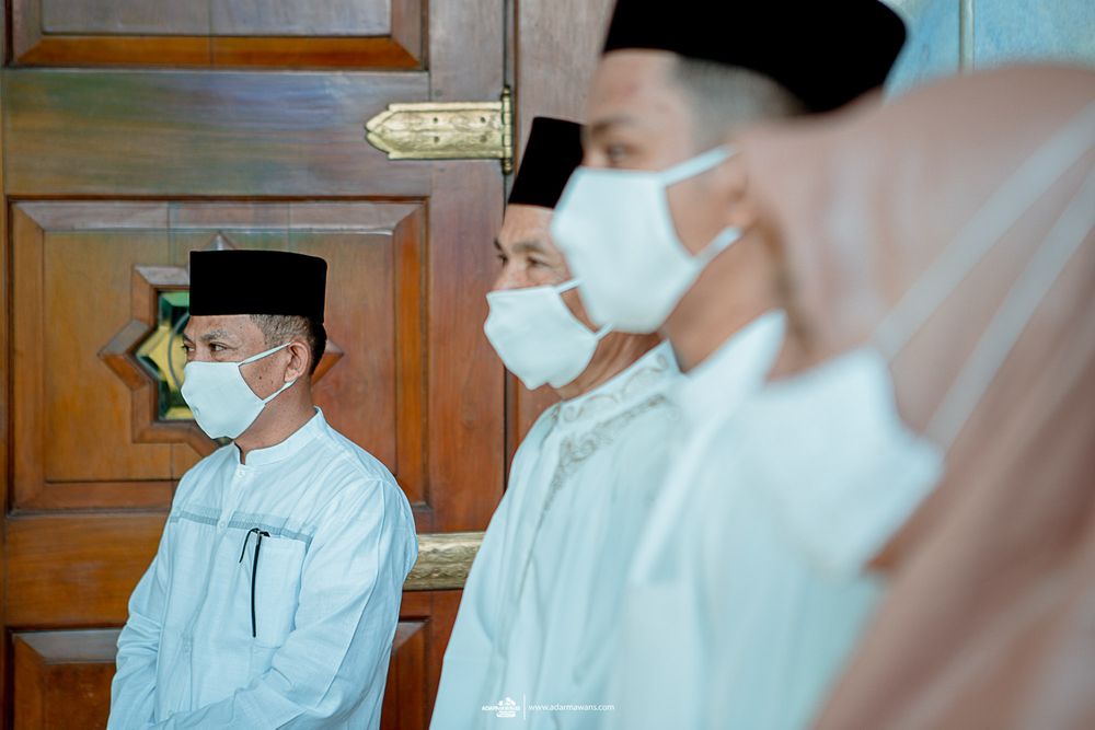 People wearing traditional Muslim caps and face masks standing in line.