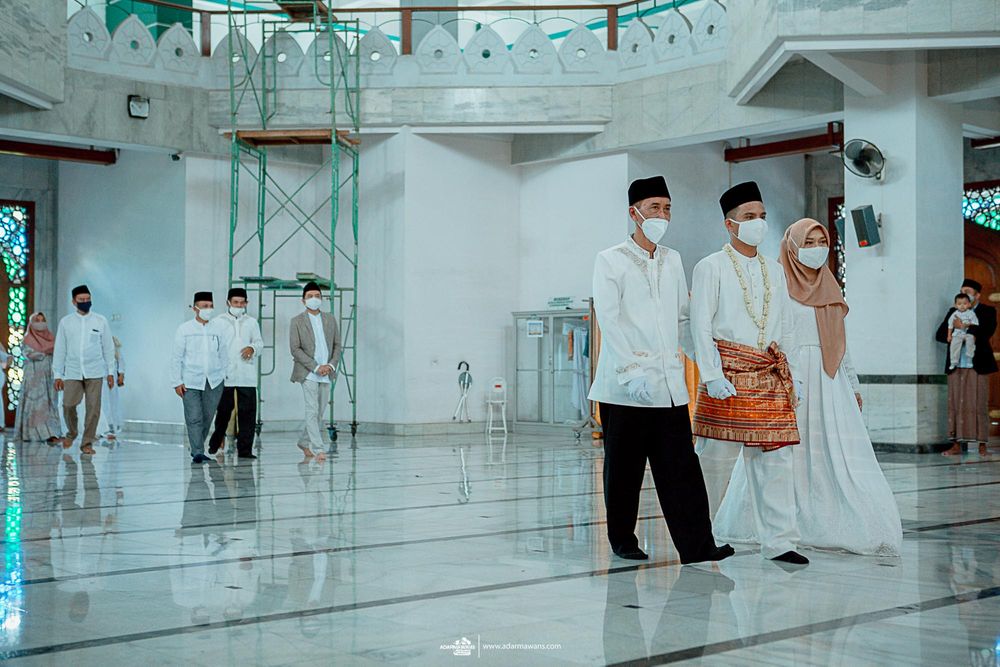 People gather inside a modern mosque with reflective marble floors and turquoise accents.