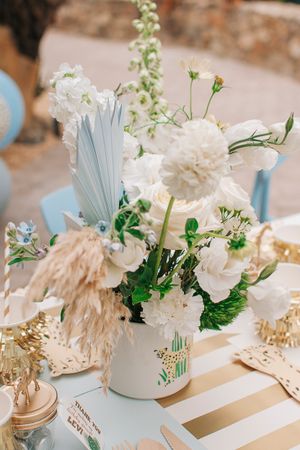 White and blue table decorations featuring fresh flowers and gold accents.