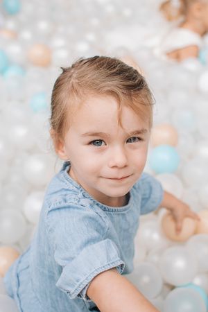 A close-up portrait of a child with bright eyes wearing denim against a soft bokeh background.