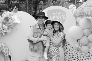 Safari-themed birthday party with balloons, giraffe decorations and a light blue sign against a white backdrop.