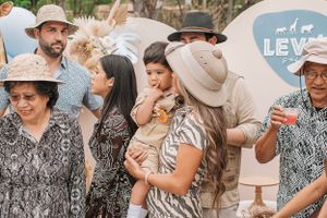 Group gathered at a safari-themed celebration with decorative balloons and natural outdoor setting.