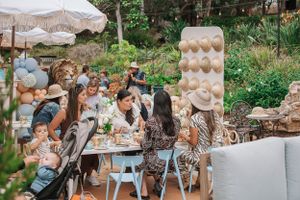 An outdoor party setup with tables, chairs, and decorative elements in a garden setting.