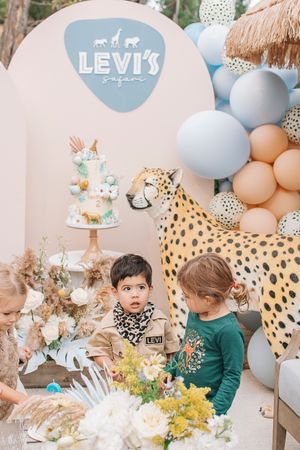 Safari-themed party decorations with blue balloons, animal prints, and floral arrangements.