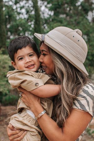 A joyful outdoor family photoshoot featuring matching safari-themed attire and natural scenery.