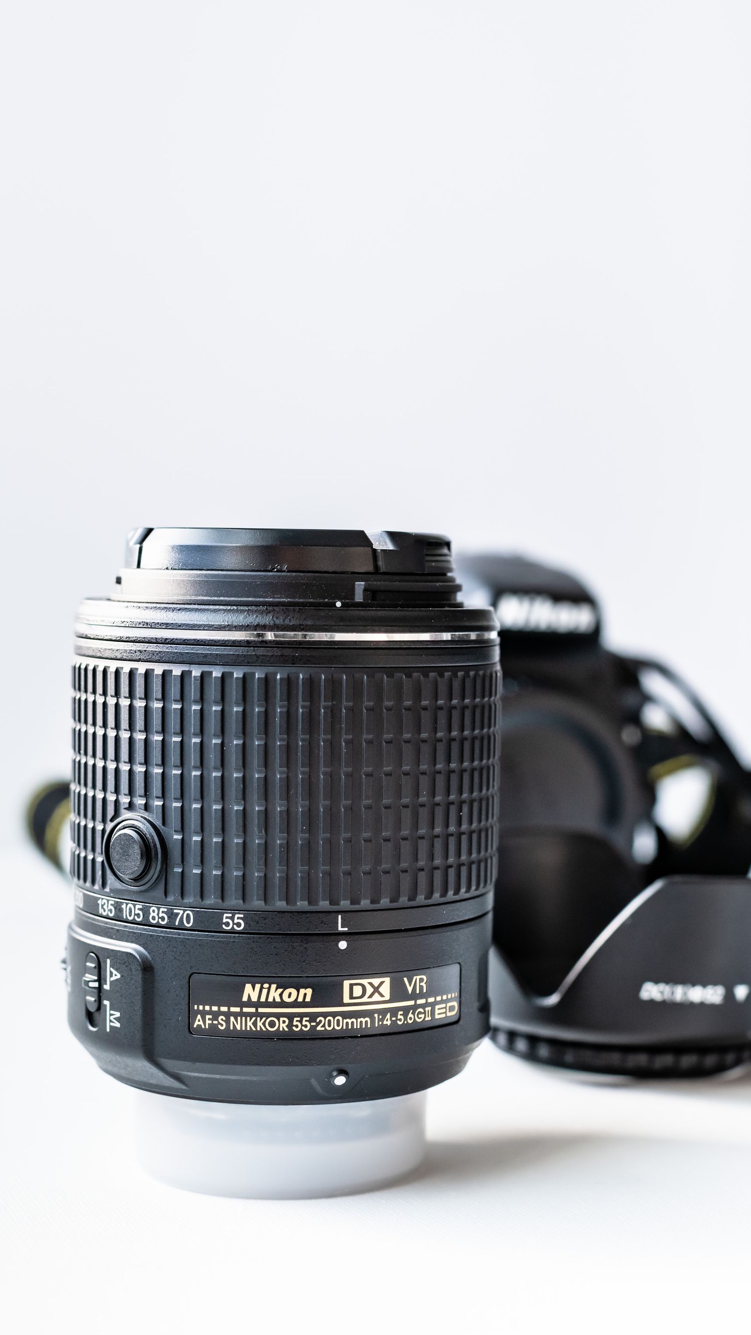 Nikon D3300 DSLR camera behind camera lens against white background