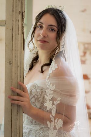 Bridal portrait series featuring delicate lace gown and flowing veil near vintage pillars.