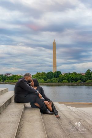 A romantic couple embraces on stone steps with the Washington Monument and Tidal Basin in the background.