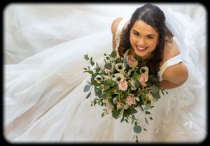 Elegant bridal portrait with flowing white veil and delicate bouquet.
