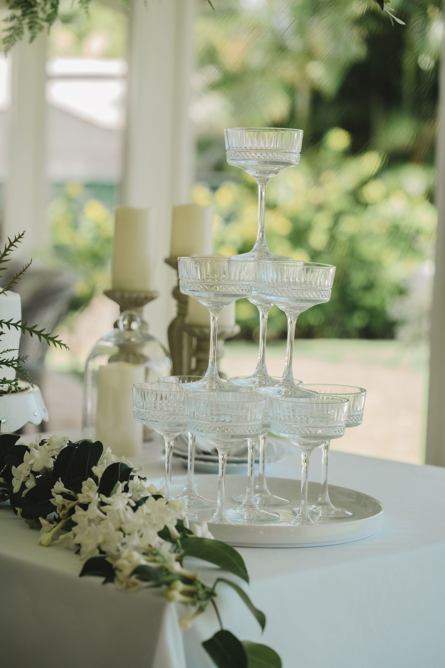 A vintage champagne tower display with white flowers at an elegant wedding reception.