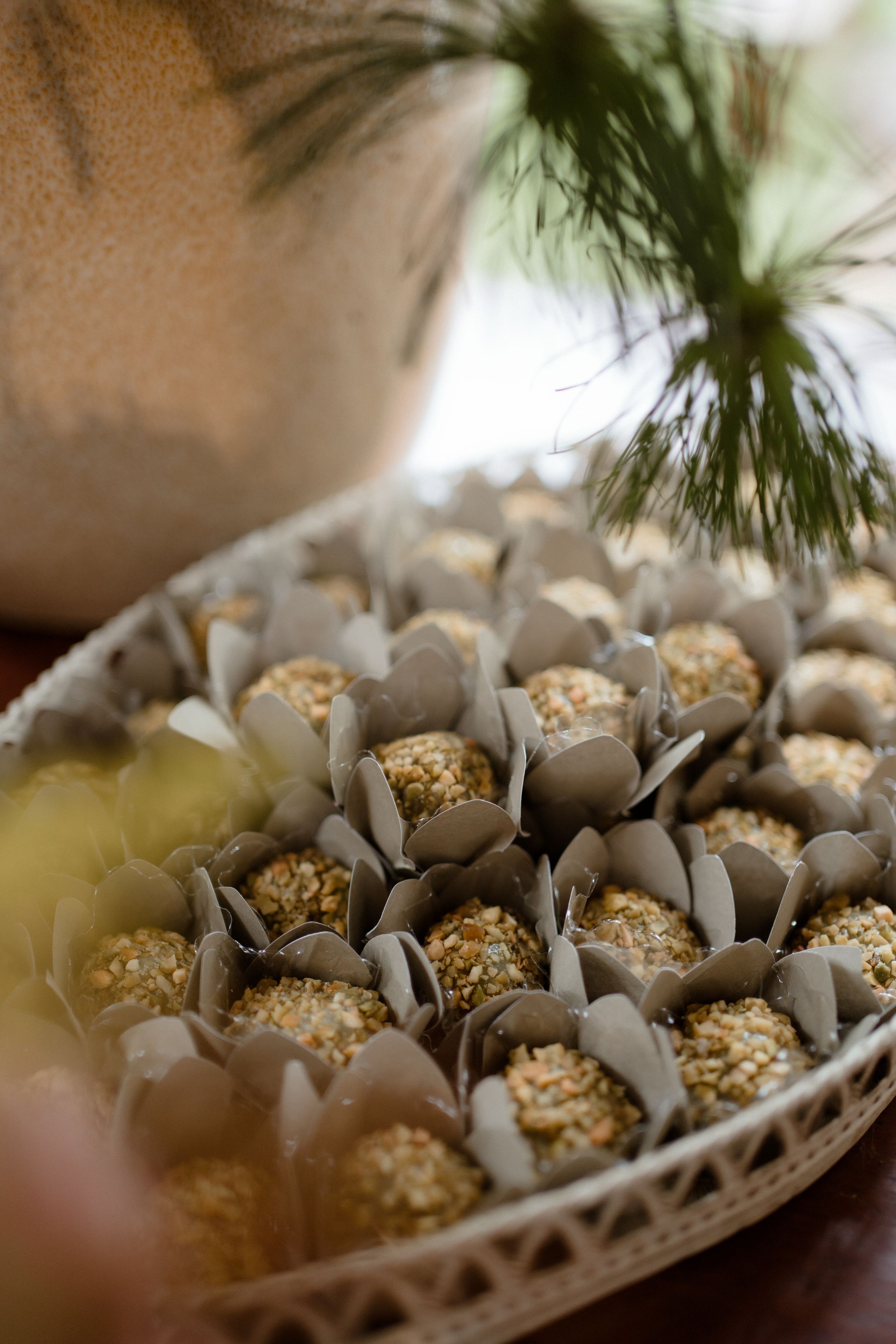 Gold dessert truffles arranged in decorative paper wrappers on a display tray.