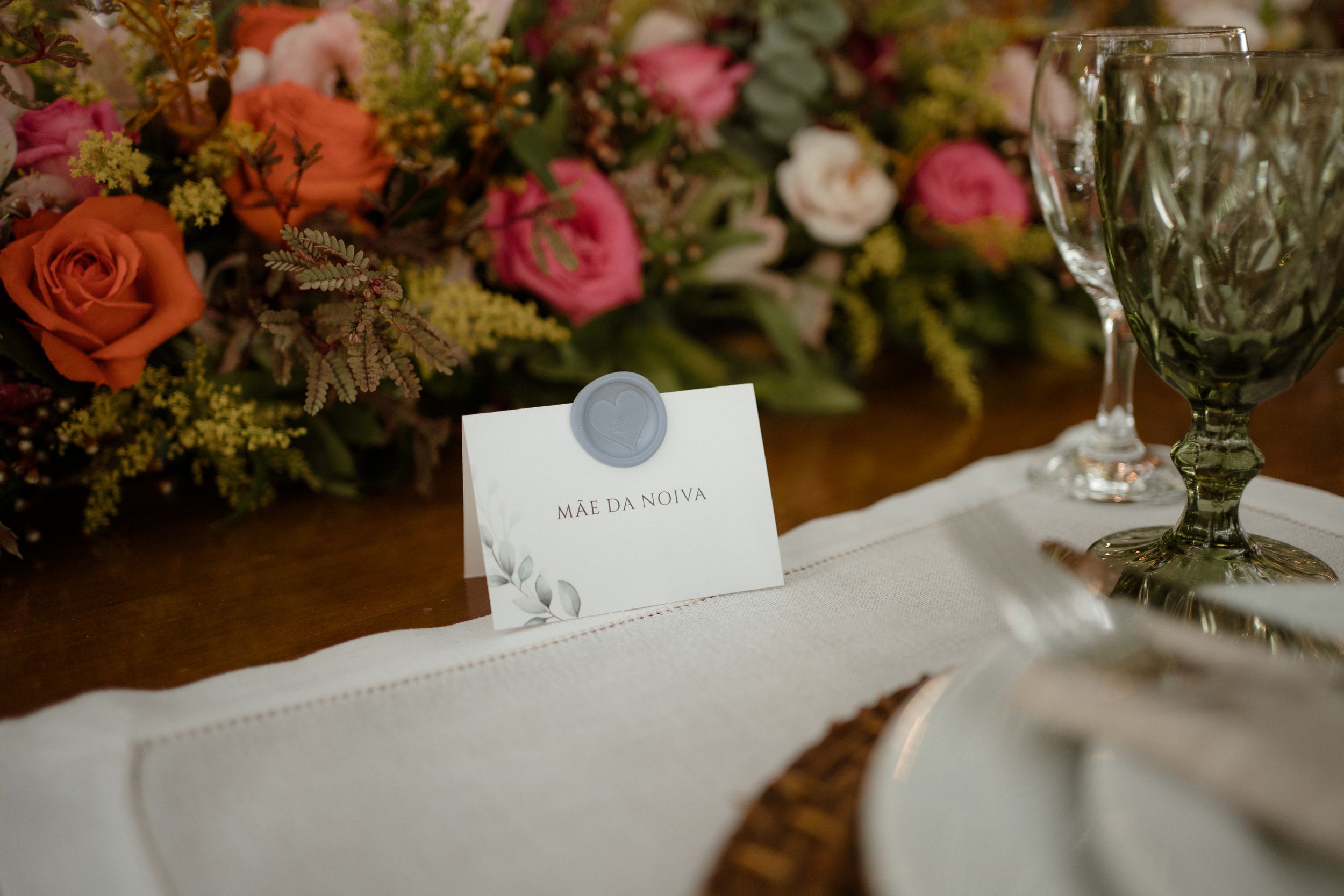 Wedding place card and table setting with pink floral arrangements and crystal glassware.