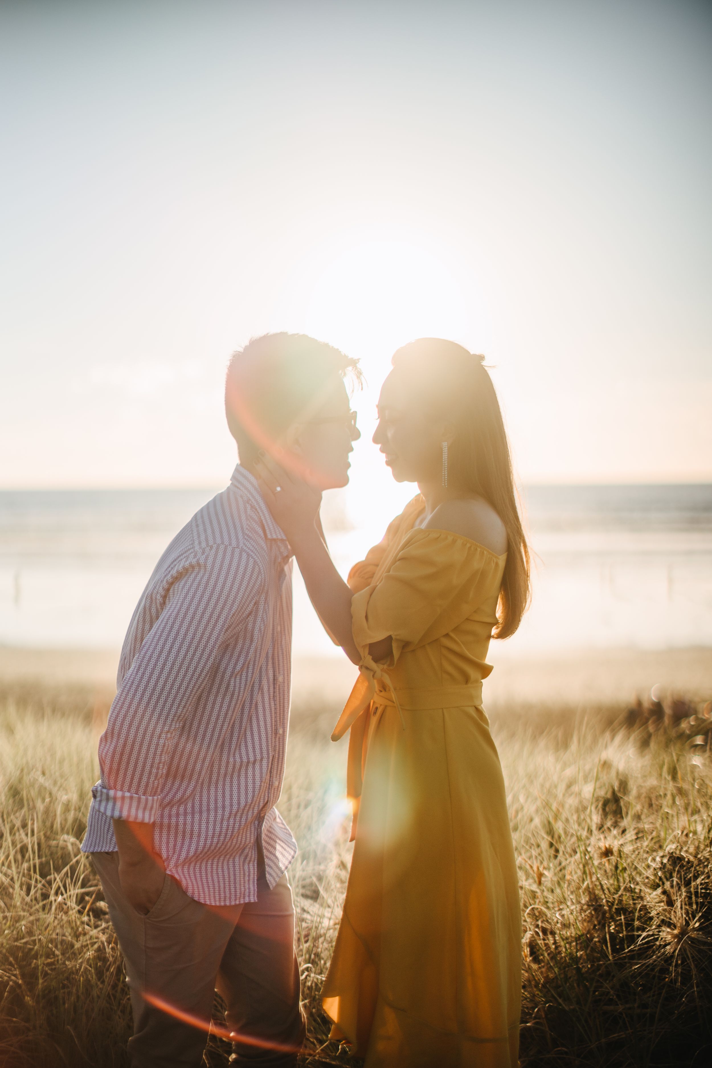 Couple posing on top of dunes at Muriwai Beach during sunset