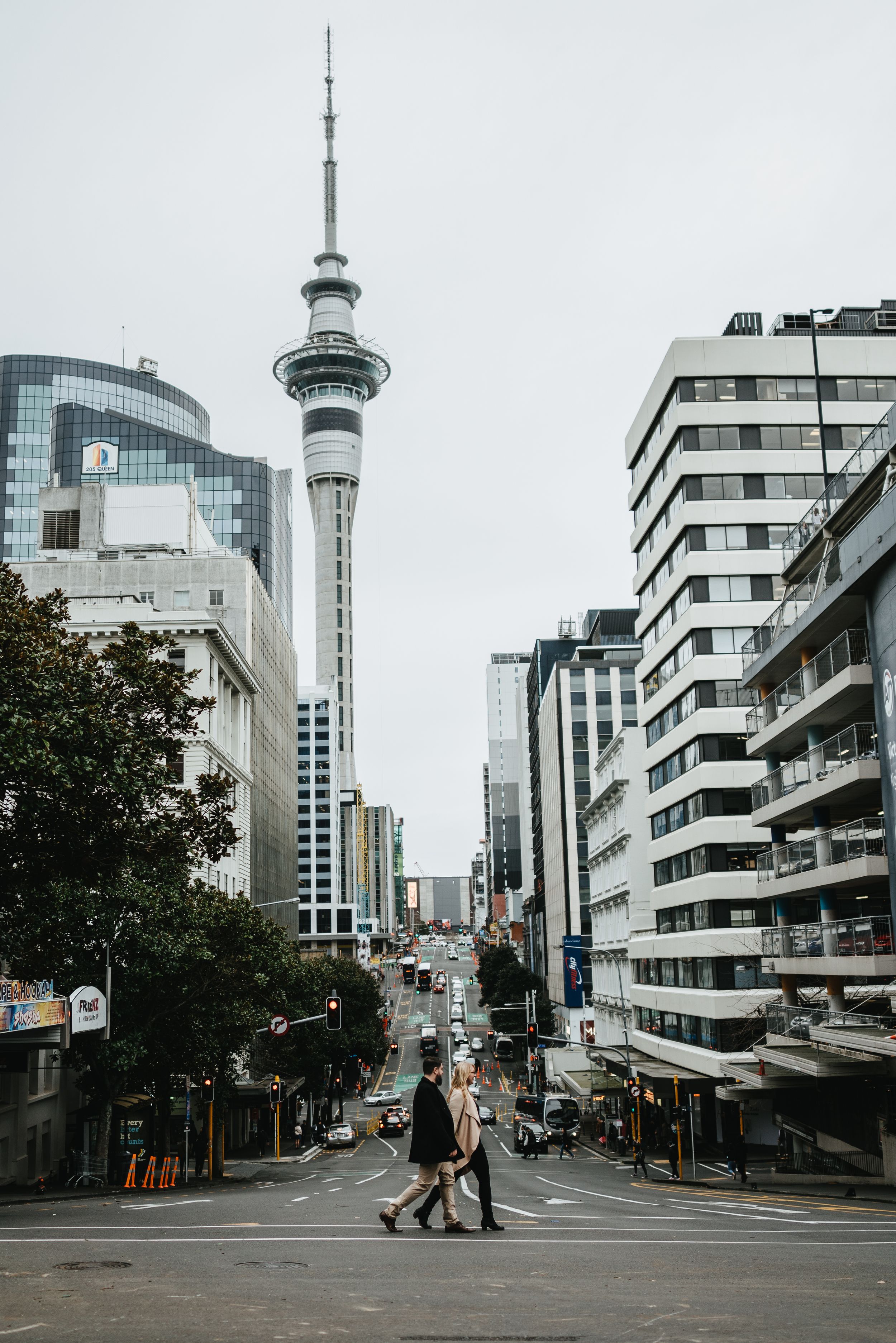Couple walking in-front of sky tower, Auckland CBD