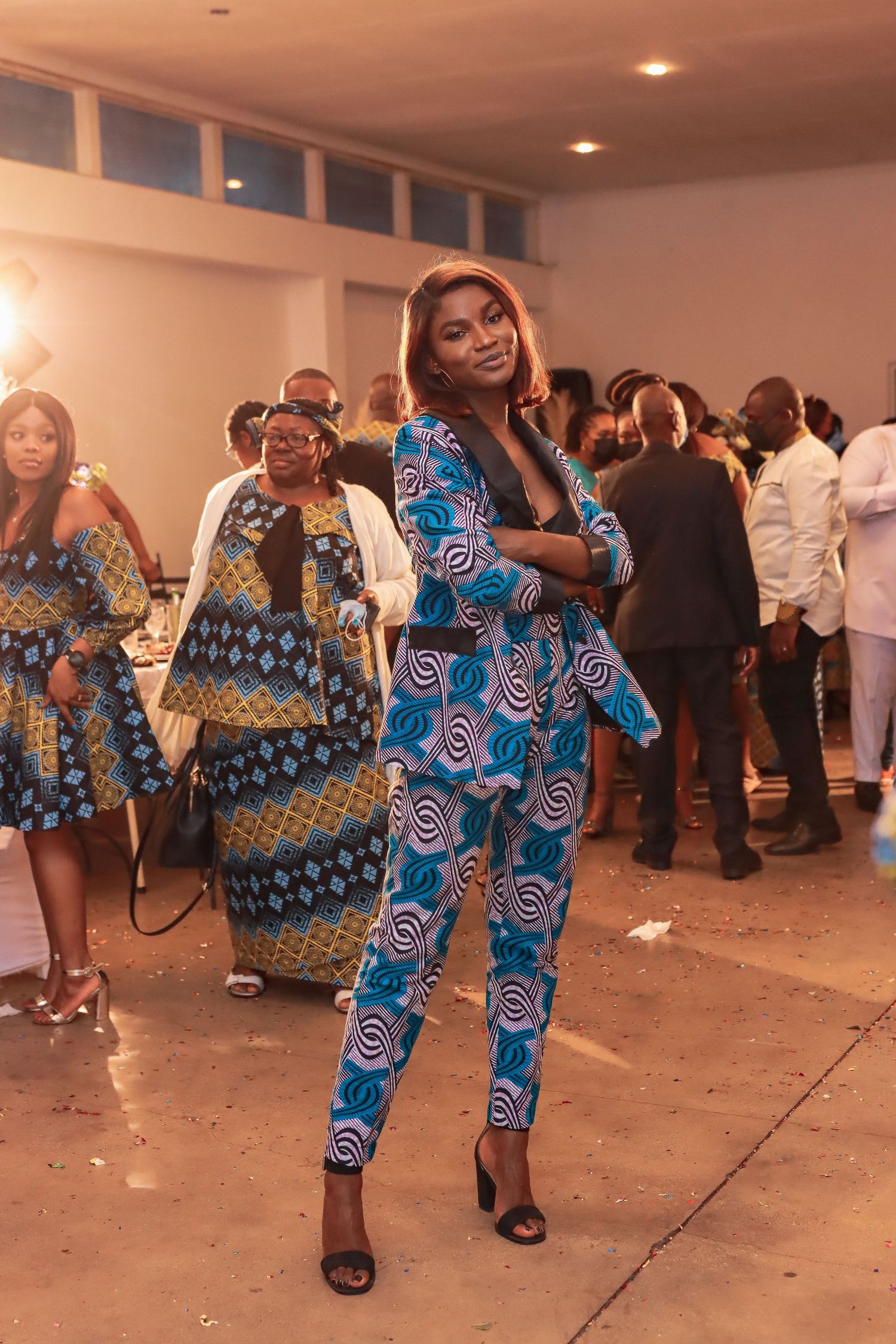 Festive gathering with attendees wearing vibrant African print outfits and dancing.