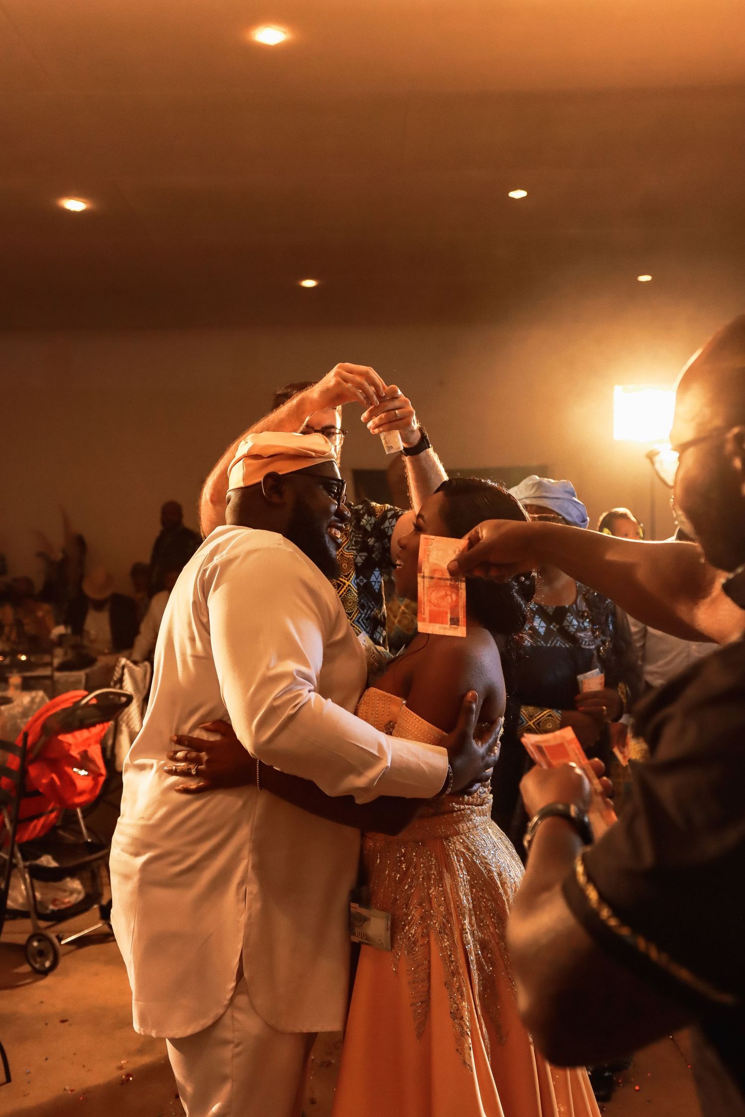 A couple dancing together at a celebration event under warm lighting.