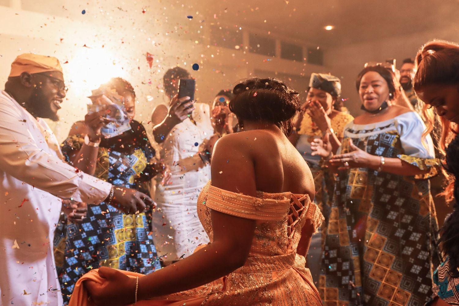 Celebratory dance scene with people in traditional African prints and formal attire.