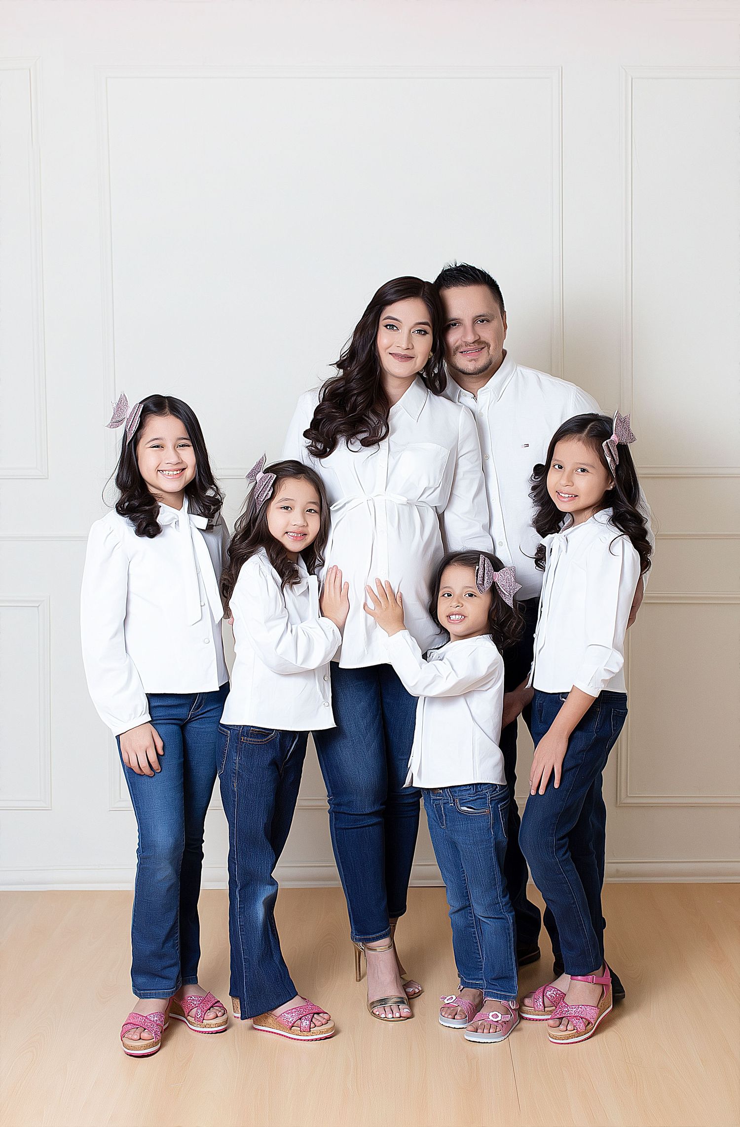 Family portrait set showing casual poses and interactions against white paneled wall.